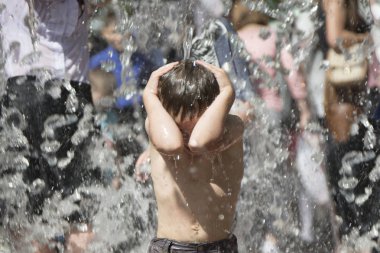 Su jetleri altında küçük oğlan. Yağan yağmur altında bir çocuk. Tsunami felaketi. Çeşme yıkanan