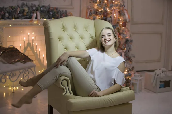 Bir Noel ağacı arka plan üzerinde genç bir kız. Kız bir deri sandalye