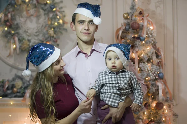 Mom dad and baby in Christmas hats A child with his parents in Christmas. Family in the New Year holidays