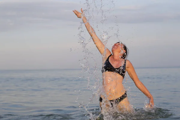 水しぶきで海水中の女性 女性の日焼けした姿は 海からジャンプします — ストック写真