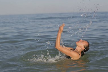 Denizde su sıçramalarına ile yaşlı kadın.