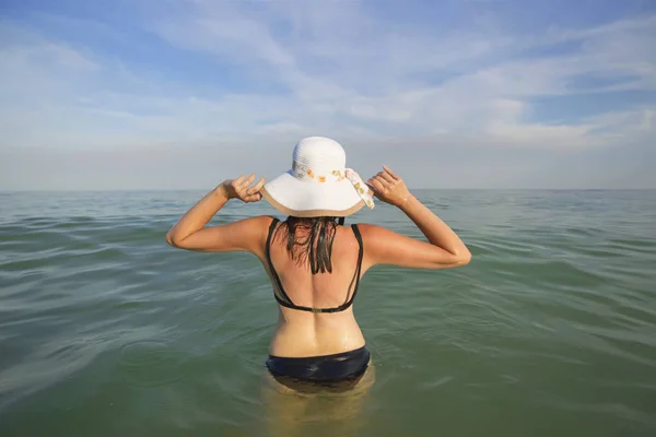 帽子を持つ女性は 海の水に入ります 海岸の休暇 — ストック写真