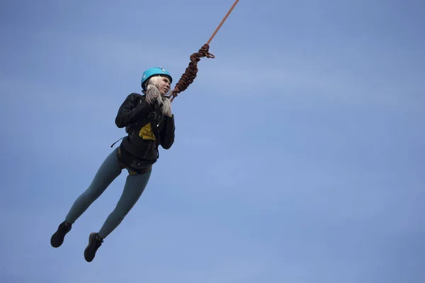 Belarus, Gomel, March 08, 2019. Jumping from the bridge to the rope.Ropejumping.Dangerous hobbies.Brave woman jumping from the bridge against the sky