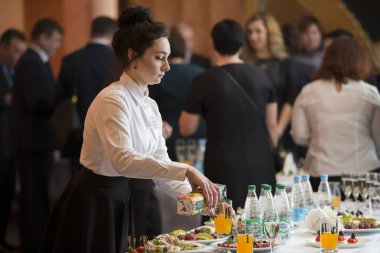 Belarus, Vitebsk, Şubat 27, 2019. Şehir restoranı. Yemek Festivali bir tepsi ile garson. Masaya bir kadın barmen koydu. Garson çalışıyor..