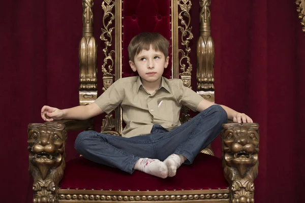 Child dreams in a royal red chair