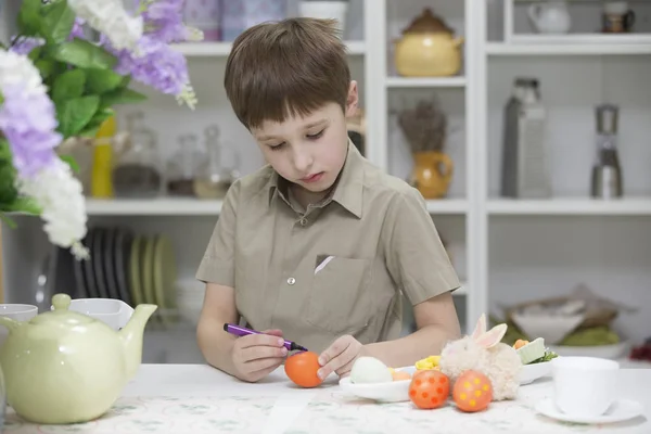 The boy in the kitchen paints Easter eggs