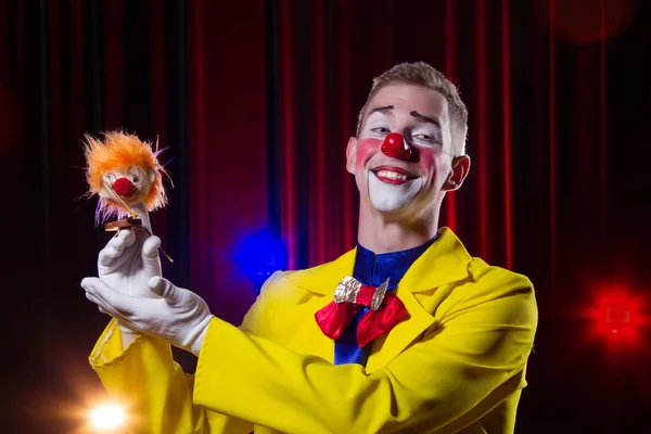 Circus clown performs number. A man in a clown outfit with a toy