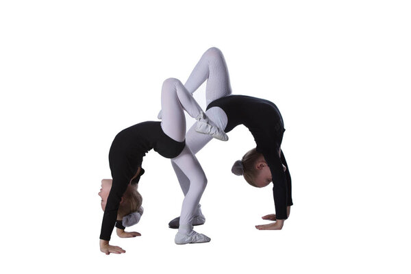 Girls gymnasts on a white background. Two little acrobats perform a number