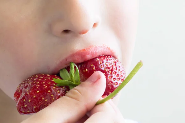 Man eats strawberries. Berry in the mouth. Small child or baby eating red color berry of strawberry