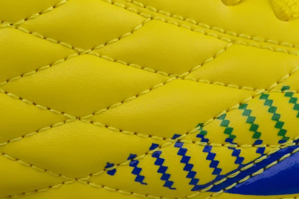 Fragment of a yellow sneaker with blue patch. The texture of the material of sports shoes