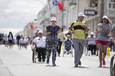 Belarus, Gimel şehri, 3 Temmuz 2019. Gençlik Festivali. Tekerlekli sandalyedeki bir adam ve sağlıklı insanlar maratona katılıyor.