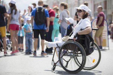 Belarus, Gimel şehri, 3 Temmuz 2019. Gençlik Festivali. Maraton engelli. Tekerlekli sandalyedeki bir kadın sıradan insanların geçmişine karşı.