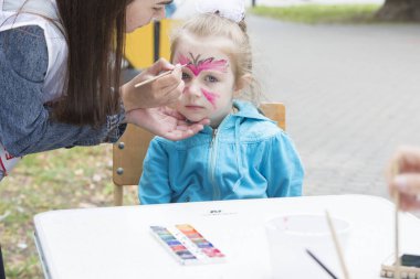 Belarus, Gimel şehri, 3 Temmuz 2019. Gençlik Festivali. Küçük kız yüz resmi çiziyor.