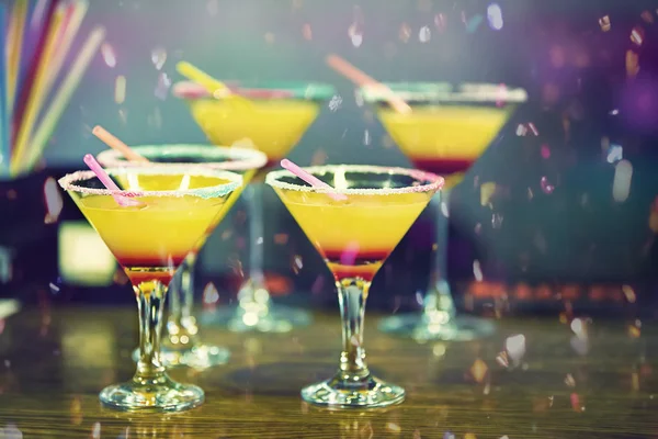 Parlak bir konfeti ile masada sarı bir kokteyl ile Gözlük. Bar tezgahında portakal içeceği.