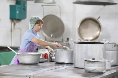 Belarus, Gomel, 2 Haziran 2017.Hastanede endüstriyel mutfak. Cook yemek hazırlar. Büyük tava ve bir kepçe ile pişirin. Kepçeli mutfak işçisi. İşçi yemek.