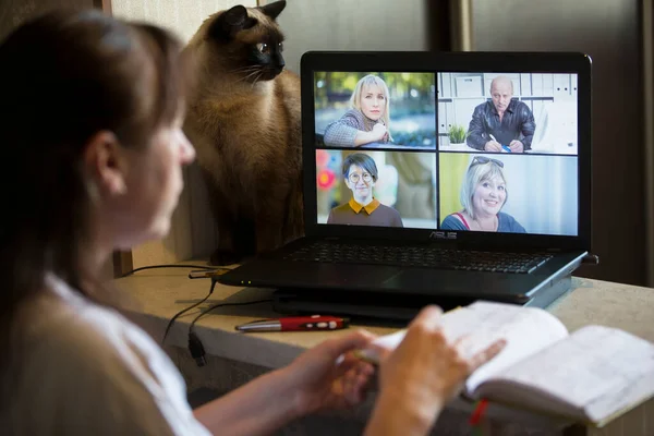 Back view of a business woman talking with her colleagues about an outline in a video conference. Business team using laptop for online meeting in video call. A group of smart people working from home.