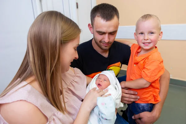 Семья с новорожденным ребенком. Мама папа и сын посмотрите на новорожденную сестру. — стоковое фото