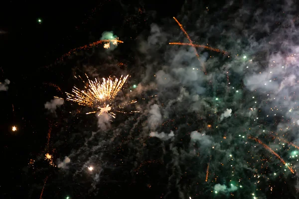 Lugares brilhantes de fogos de artifício e fumaça colorida em um fundo preto. — Fotografia de Stock