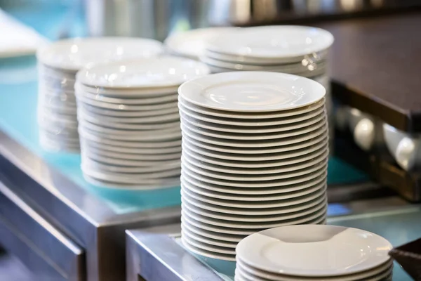 Stacks of empty white plates on a restaurant table. — Stock Photo, Image