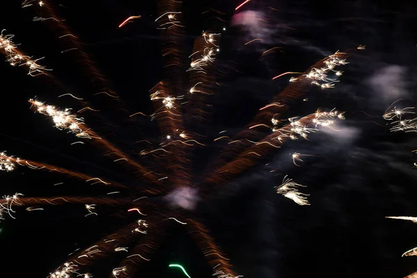 Lugares claros de fogos de artifício da cor de ouro em uma exposição longa em um contexto preto. Fundo festivo. — Fotografia de Stock