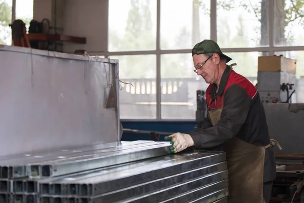 Lavoratore in officina con tubi di ventilazione in metallo. — Foto Stock