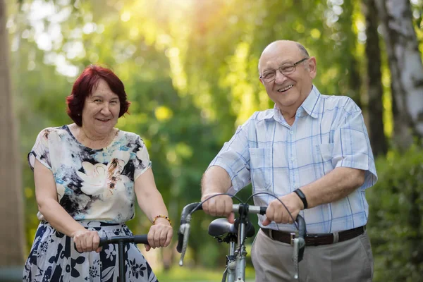 Happy elderly couple with a bicycle. Handsome man and woman senior citizens. Husband and wife of old age for a walk.