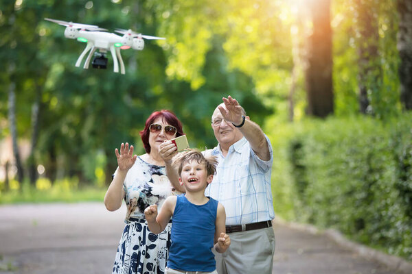 Happy elderly couple with a grandson on a walk. An elderly husband and wife and child launch a drone.