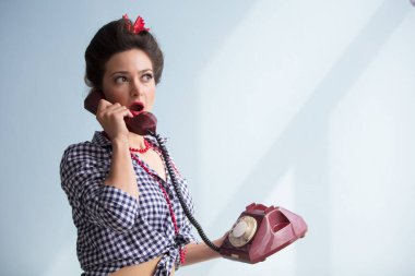 Retro kız eski bir telefonla konuşuyor. Yüzünde şaşkınlık hissi var..