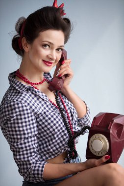 50 'lerin tarzında bir kadın. Güzel retro kız eski bir telefonla konuşuyor..