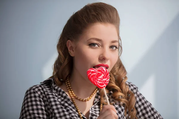 Mooi meisje met een rood snoep in de vorm van een hart — Stockfoto