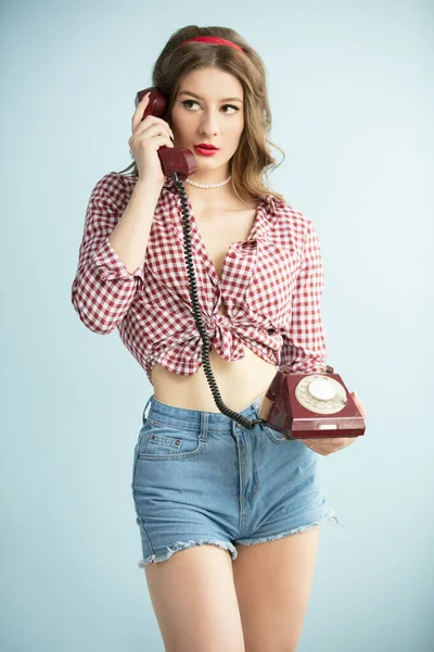 Frau im Stil der fünfziger Jahre. Junge Retro-Frau in Jeanshosen mit altem Telefon. — Stockfoto