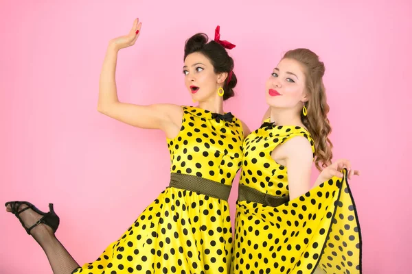 Chicas retro. Dos mujeres en vestidos amarillos sobre un fondo rosa. — Foto de Stock