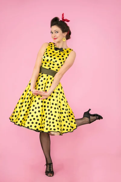 Retro girl. Beautiful woman in a dress with polka dots on heels on a bright background. — Stock Photo, Image
