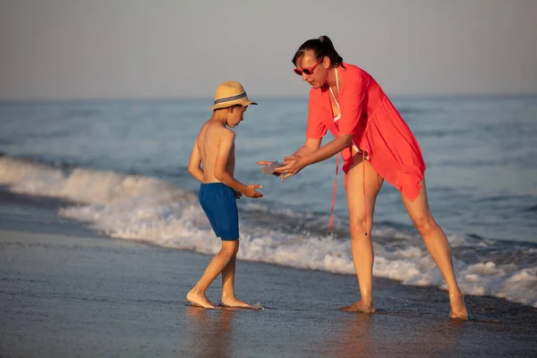 Mamma mostra a suo figlio una medusa sulla costa. Donna con un bambino in vacanza al mare. — Foto Stock