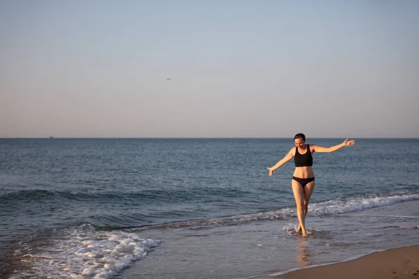 Kobieta w średnim wieku spaceruje po plaży w kostiumie kąpielowym. — Zdjęcie stockowe