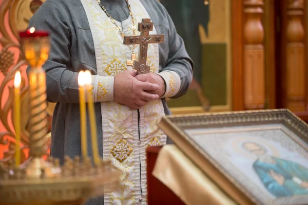 Sacerdotes mão com uma cruz no fundo das velas da igreja. — Fotografia de Stock