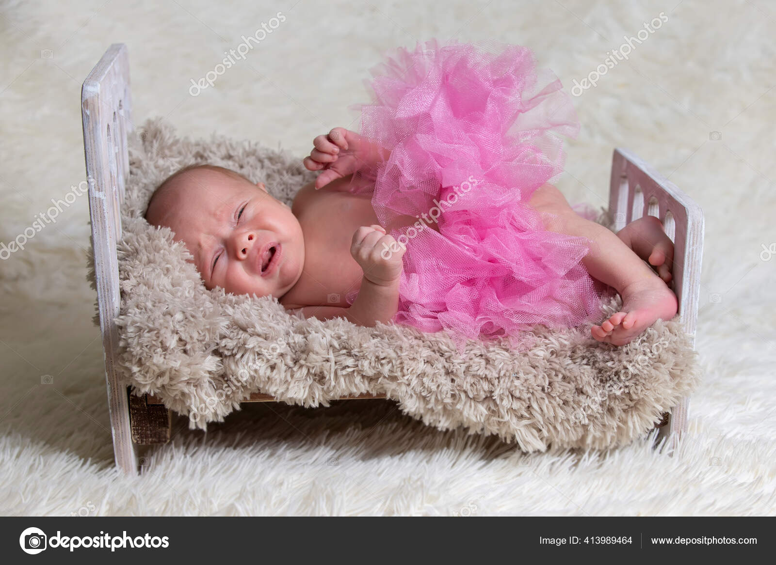 Bebé recién nacido llorando en la cuna. Bebé con una falda rosa en una cama  de piel. — Foto de stock #413989464 © aspsvz, image size:1600x1166