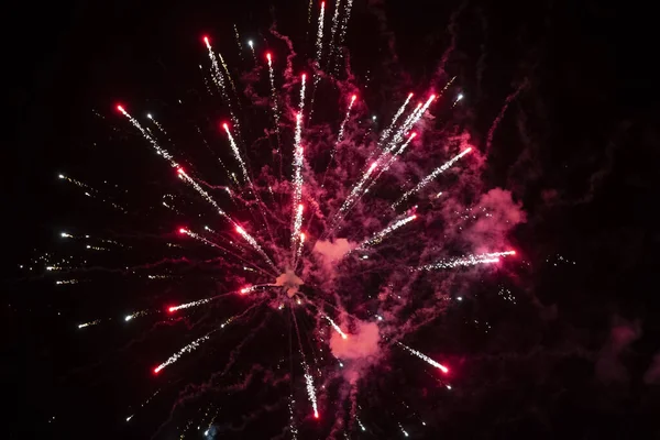 Macchie rosse di fuochi d'artificio in fumo su uno sfondo nero. Sfondo festivo. — Foto Stock