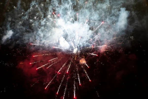 Macchie rosse di fuochi d'artificio in fumo su uno sfondo nero. Sfondo festivo. — Foto Stock