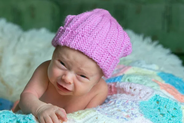 Bebé recién nacido con cara graciosa. Pequeño bebé con gorra rosa está llorando. — Foto de Stock