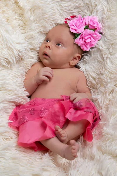 Hermosa niña recién nacida en ropa rosa en una cama de piel. — Foto de Stock