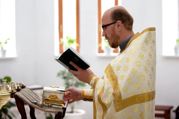 15 de julho de 2020 Belarus, cidade de Gomel. Igreja da cidade. O sacerdote lê uma oração com a Bíblia em suas mãos. — Fotografia de Stock