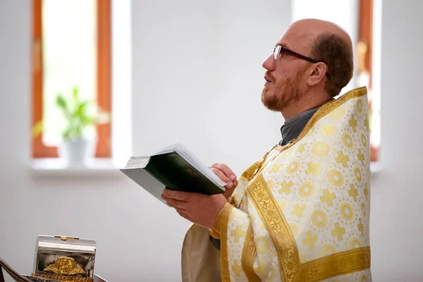 15 de julho de 2020 Belarus, cidade de Gomel. Igreja da cidade. O sacerdote lê uma oração com a Bíblia em suas mãos. — Fotografia de Stock