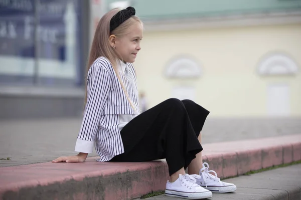 Маленькая девочка сидит на обочине в городской среде. — стоковое фото