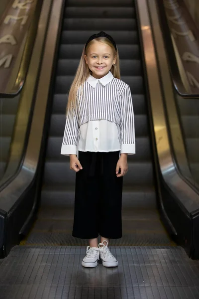 Маленькая девочка с светлыми волосами стоит у экскалатора метро. — стоковое фото