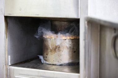 Tüttürmek için endüstriyel bir fırında talaş ve dumanla metal tencere..