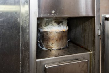 Tüttürmek için endüstriyel bir fırında talaş ve dumanla metal tencere..
