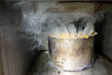 Tüttürmek için endüstriyel bir fırında talaş ve dumanla metal tencere..