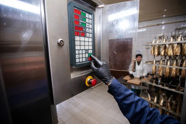 September 18, 2020. Belarus, Gamil. Fish factory.A worker turns on an industrial oven for smoking fish.