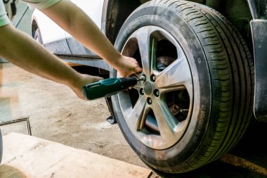 Tamirci üstünde belgili tanımlık tekerlek fındık unscrews. Adam değiş tokuşu lastik. Lastik servisi. Lastik montaj.